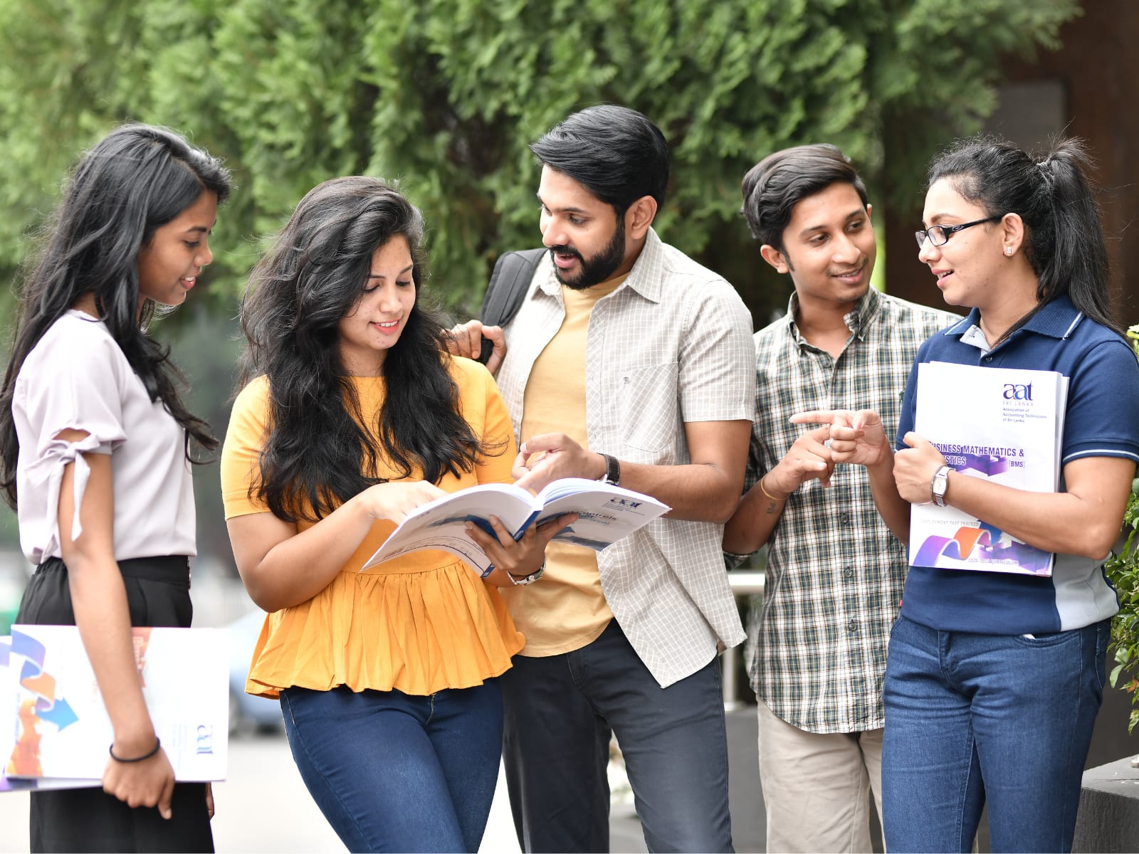 A group of Indian students reading a book together outdoors